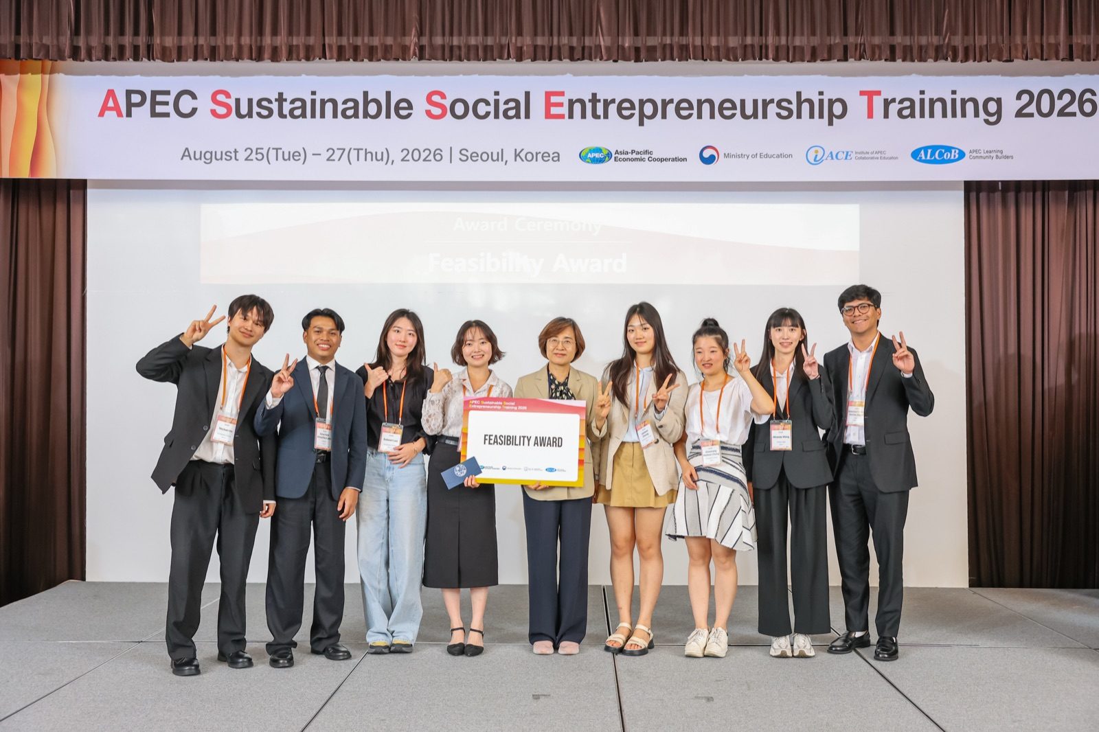 APEC 현수막 아래 무대에서 팀원 여덟 명과 시상자가 ‘FEASIBILITY AWARD’ 판을 가운데 두고 브이를 하며 서 있다.