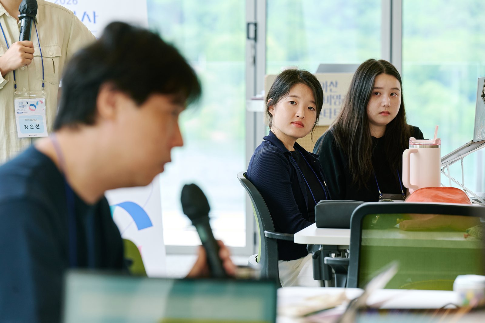 워크숍 자리에 정진서랑과 이주연이 나란히 앉아 발표를 듣고 있다.