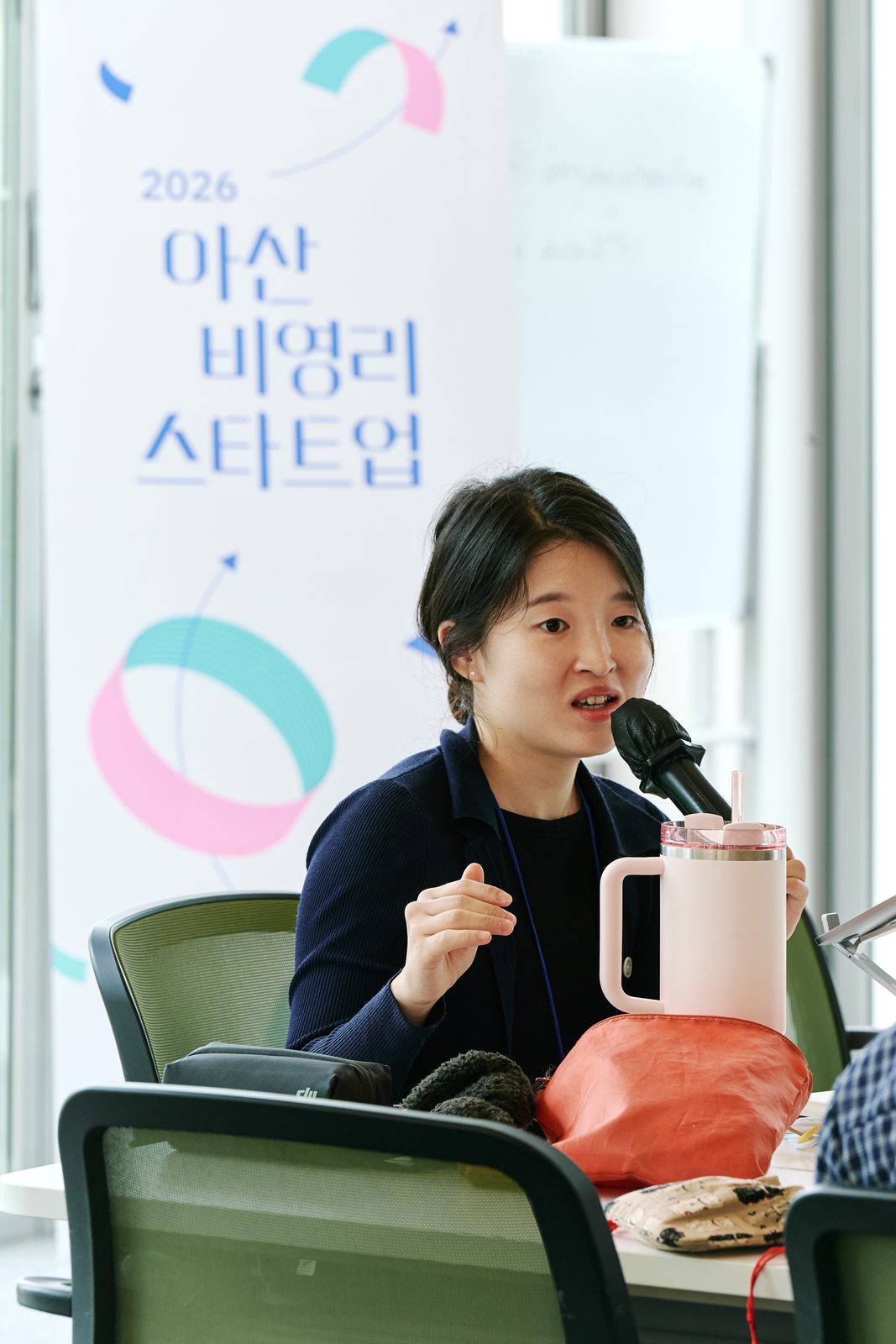 아산 비영리스타트업 현수막 앞에서 정진서랑이 마이크를 잡고 발표하고 있다.
